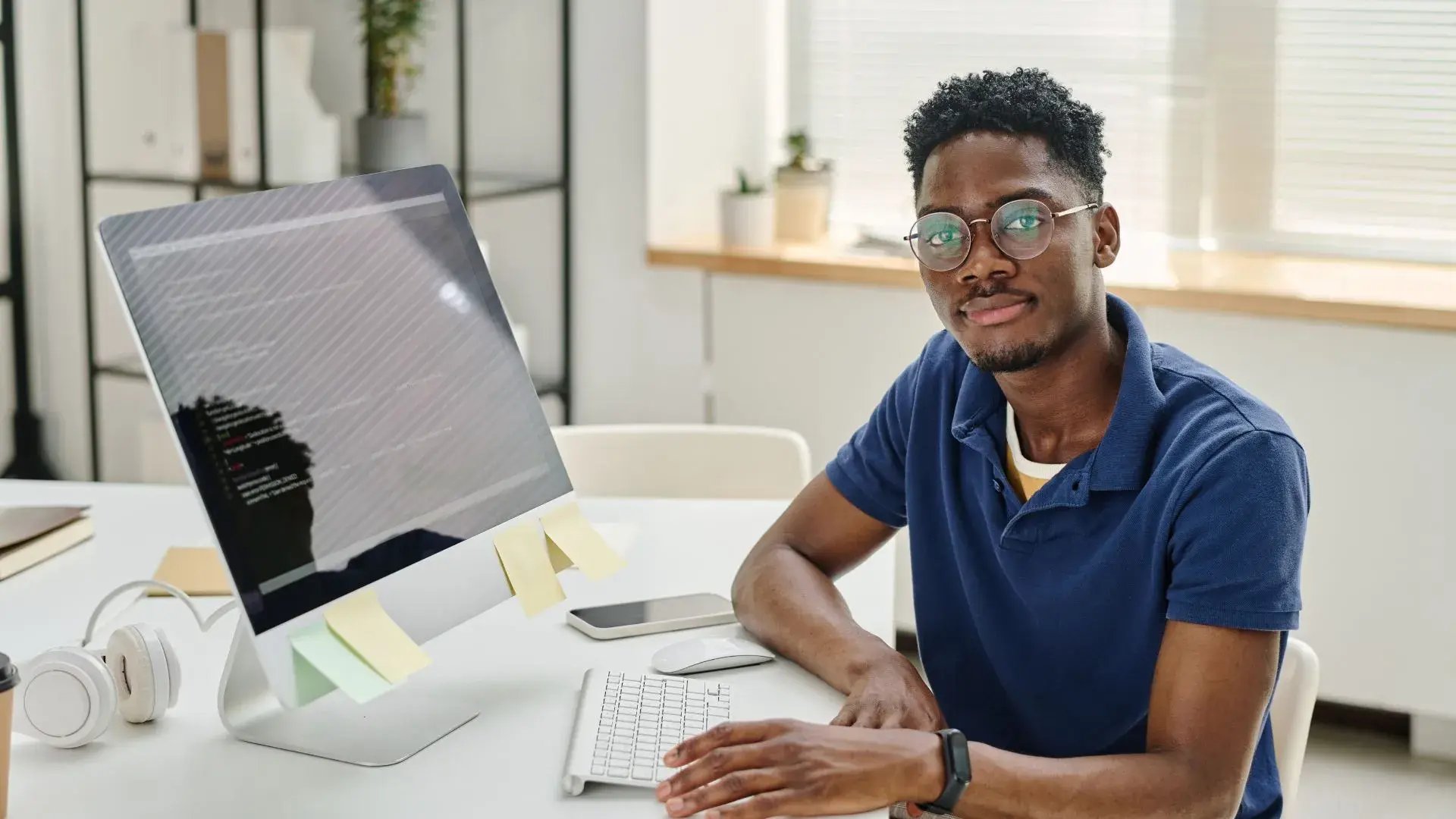 A male office worker in his desk looking at the camera