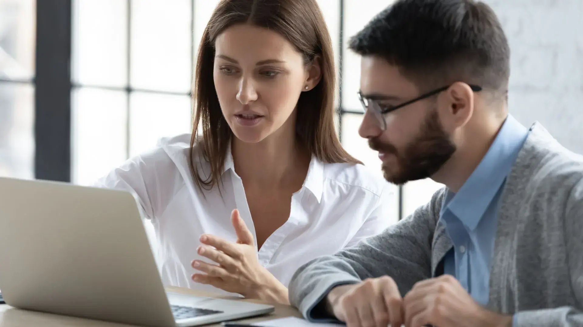 A manager talks to her staff over an open laptop screen