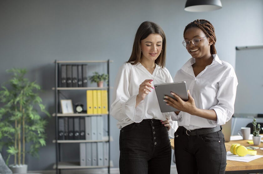 Two women using tablet to learn best practices in cybersecurity for tech companies