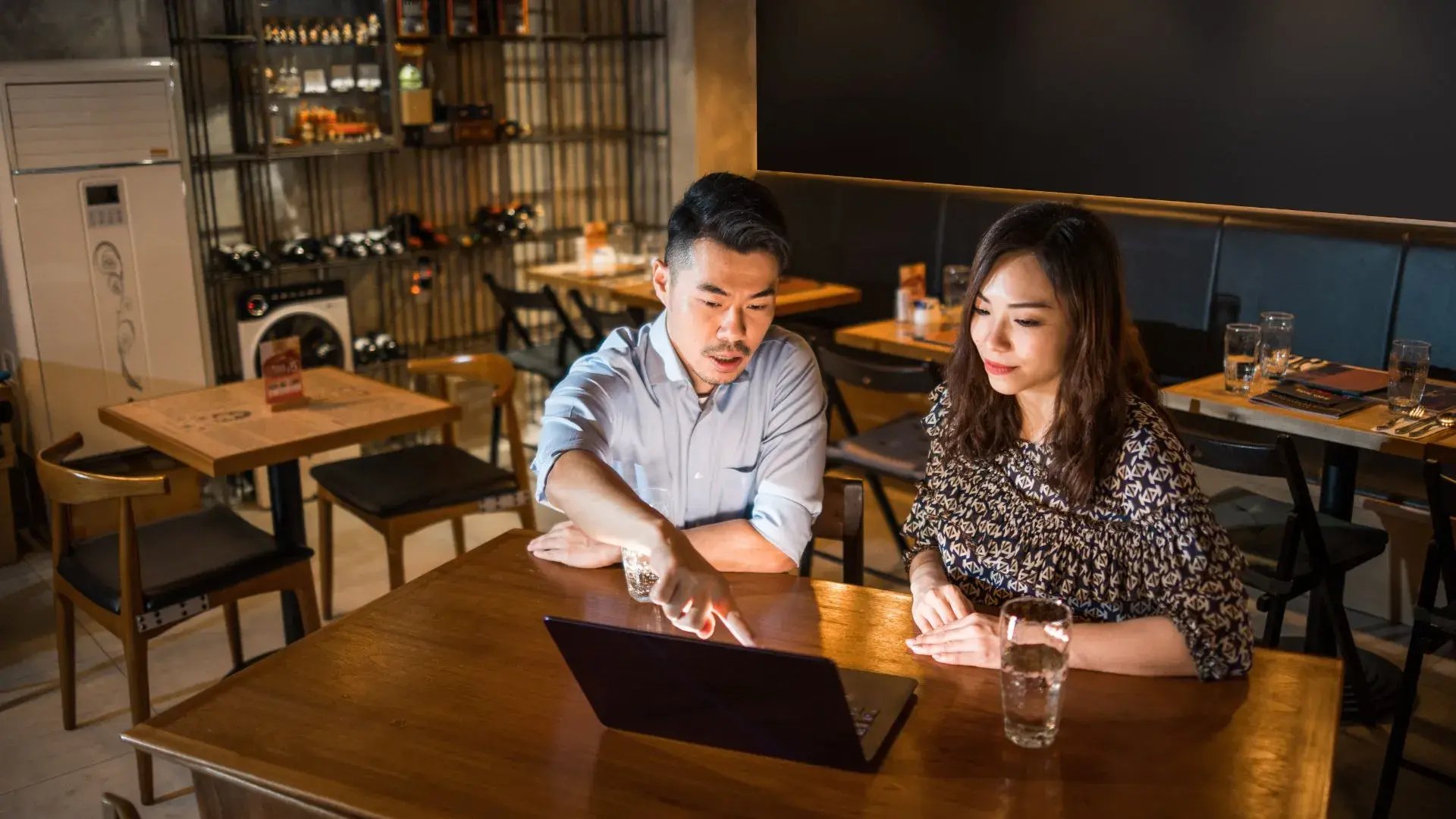 A male and a female business owner are having a discussion&nbsp; while using their laptop
