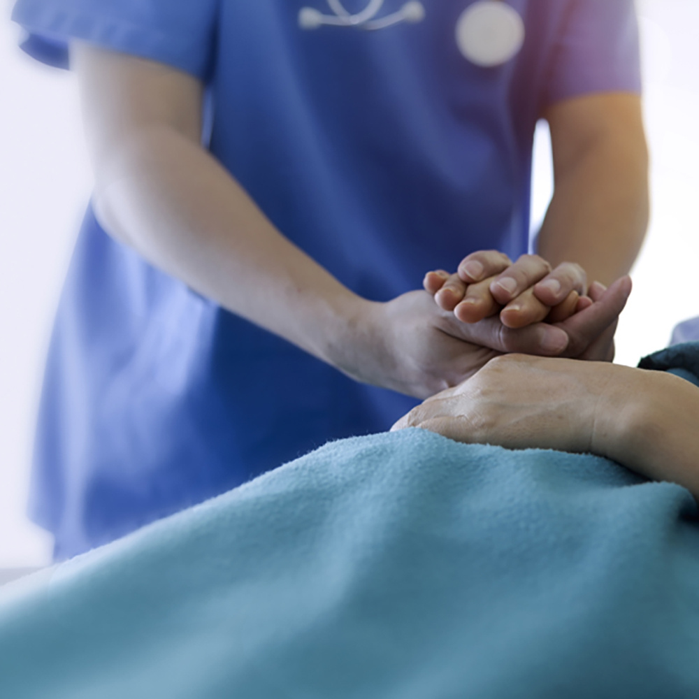 Nurse holding the hand of a patient in a hospital bed