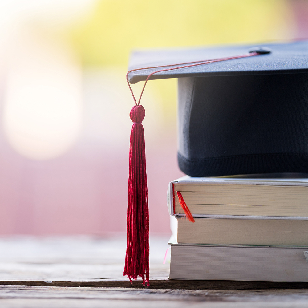 Graduation cap with tassle on top of stacked books