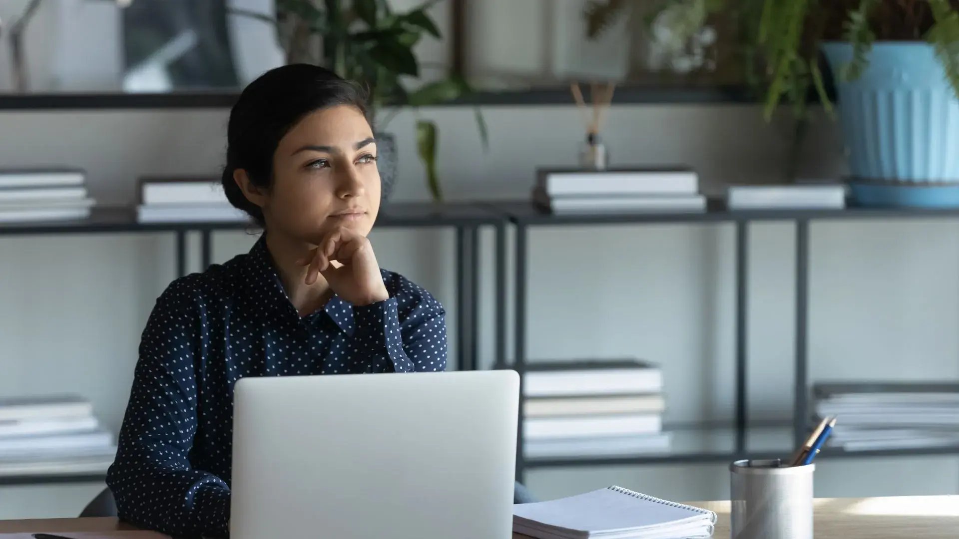 A female employee in deep thought with her laptop open